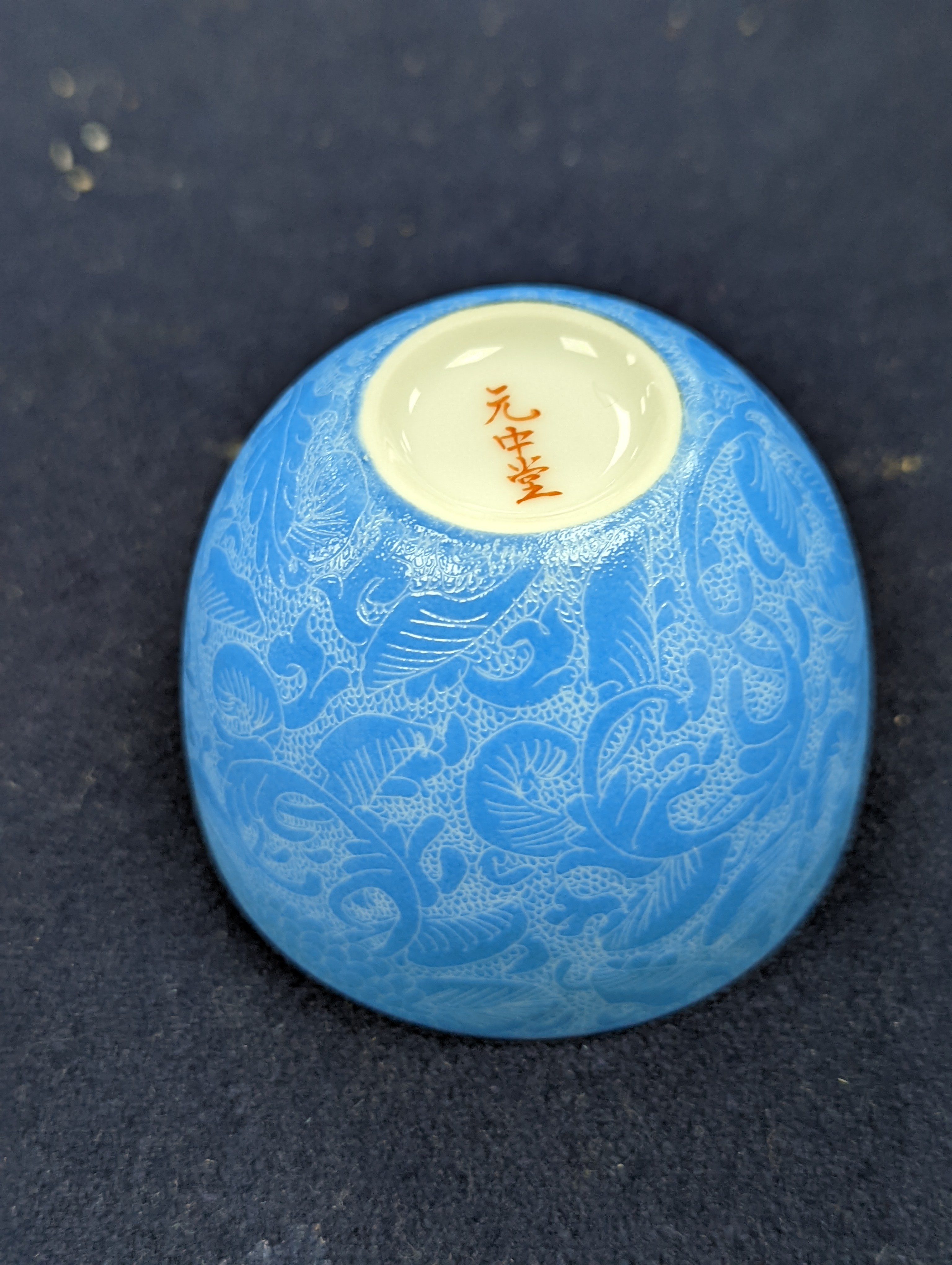 A Japanese or Chinese sgrafitto blue enamelled cup, cased. 6cm diameter